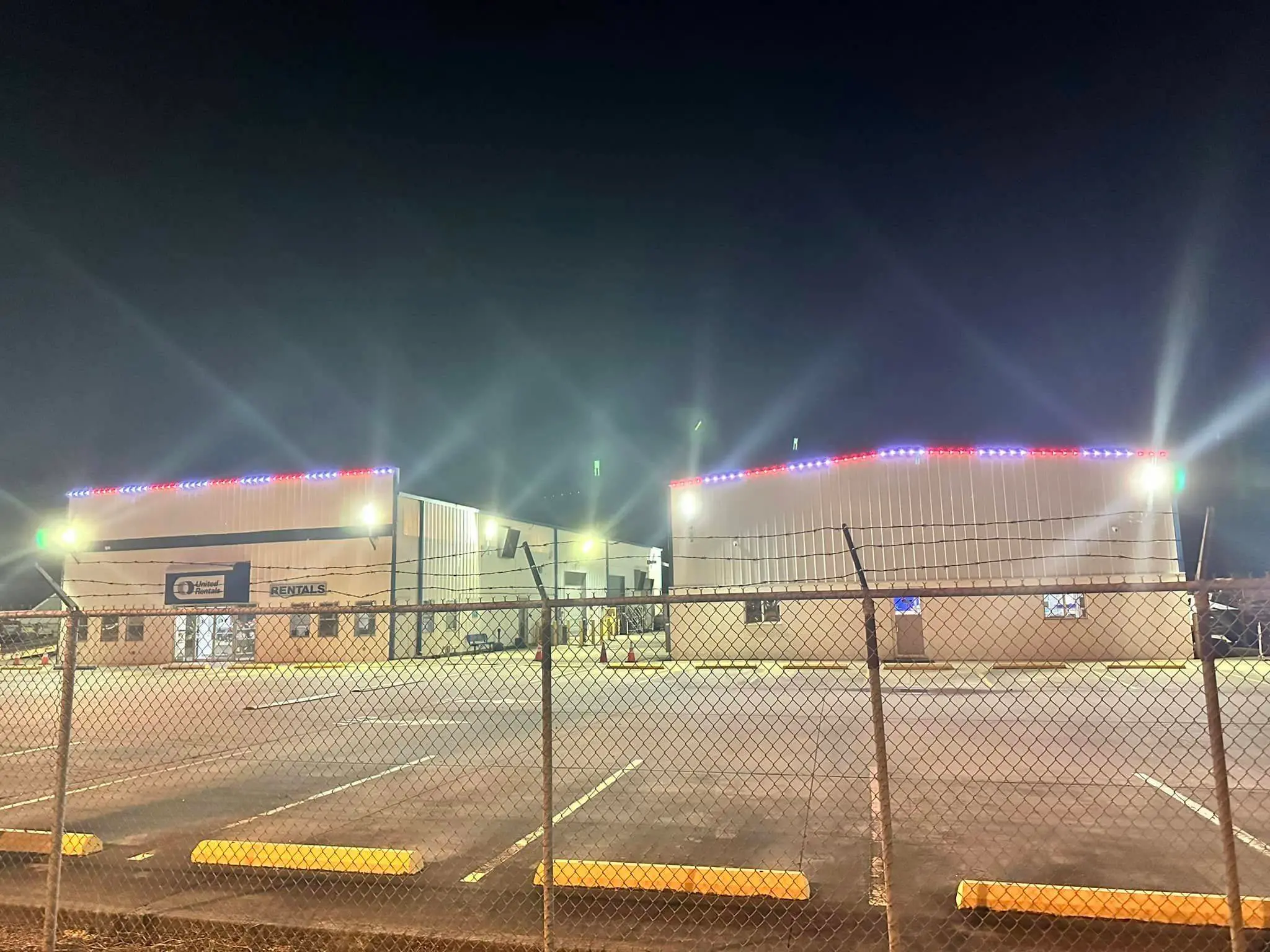 Metal commercial building at dusk with blue, red, and amber Trimlight along the roof.